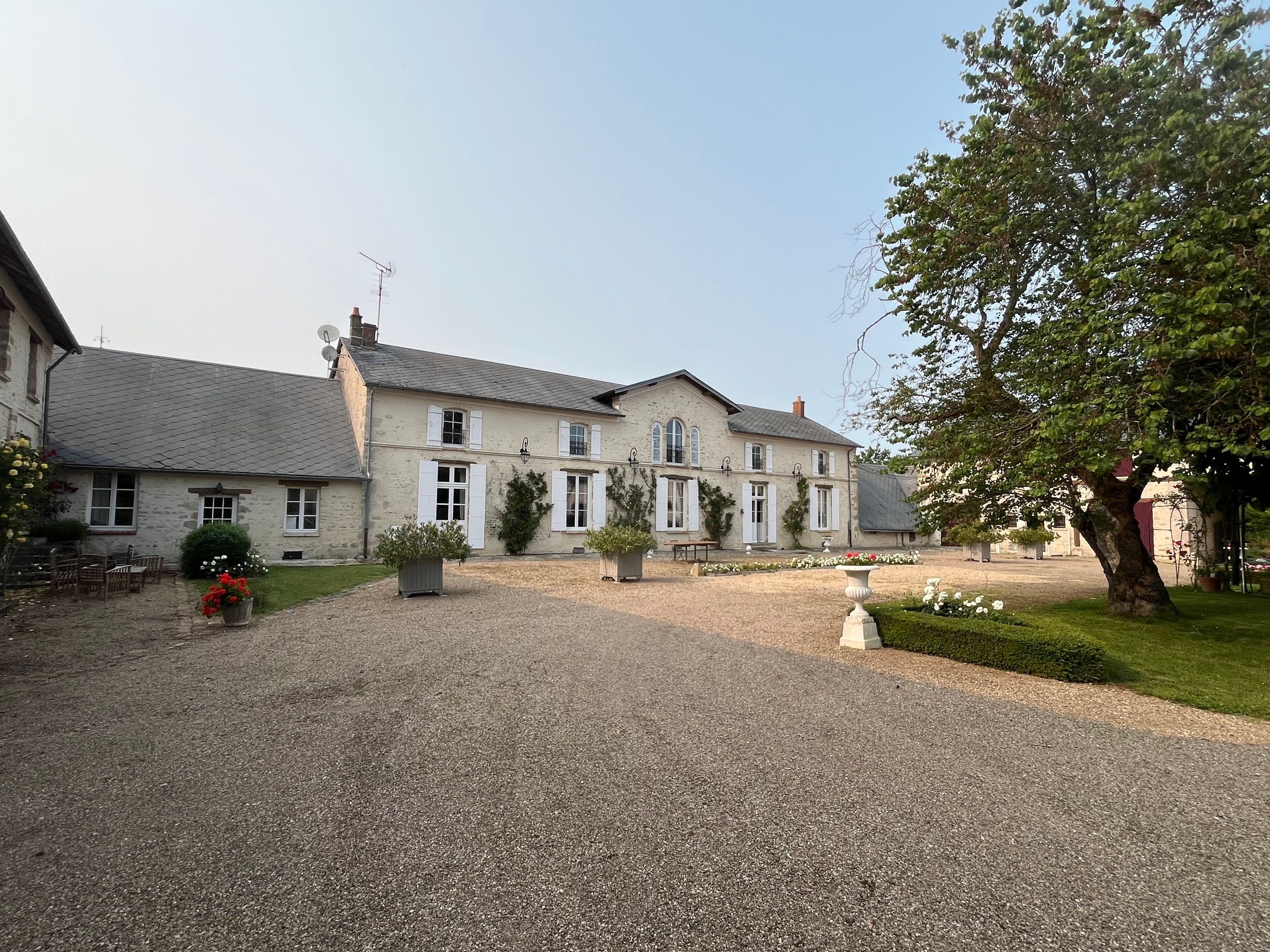 La cour du domaine et la façade de La Maison, en pierre blonde, un matin clair