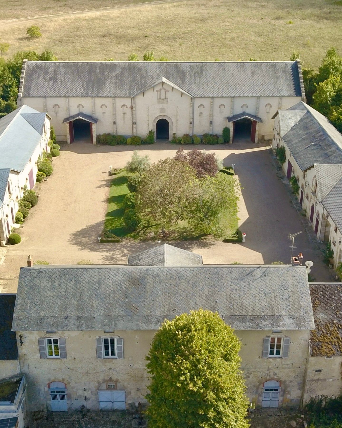 Vue aérienne de la cour fermée du domaine, entourée de La Grange, La Plume, Les Écuries et La Maison