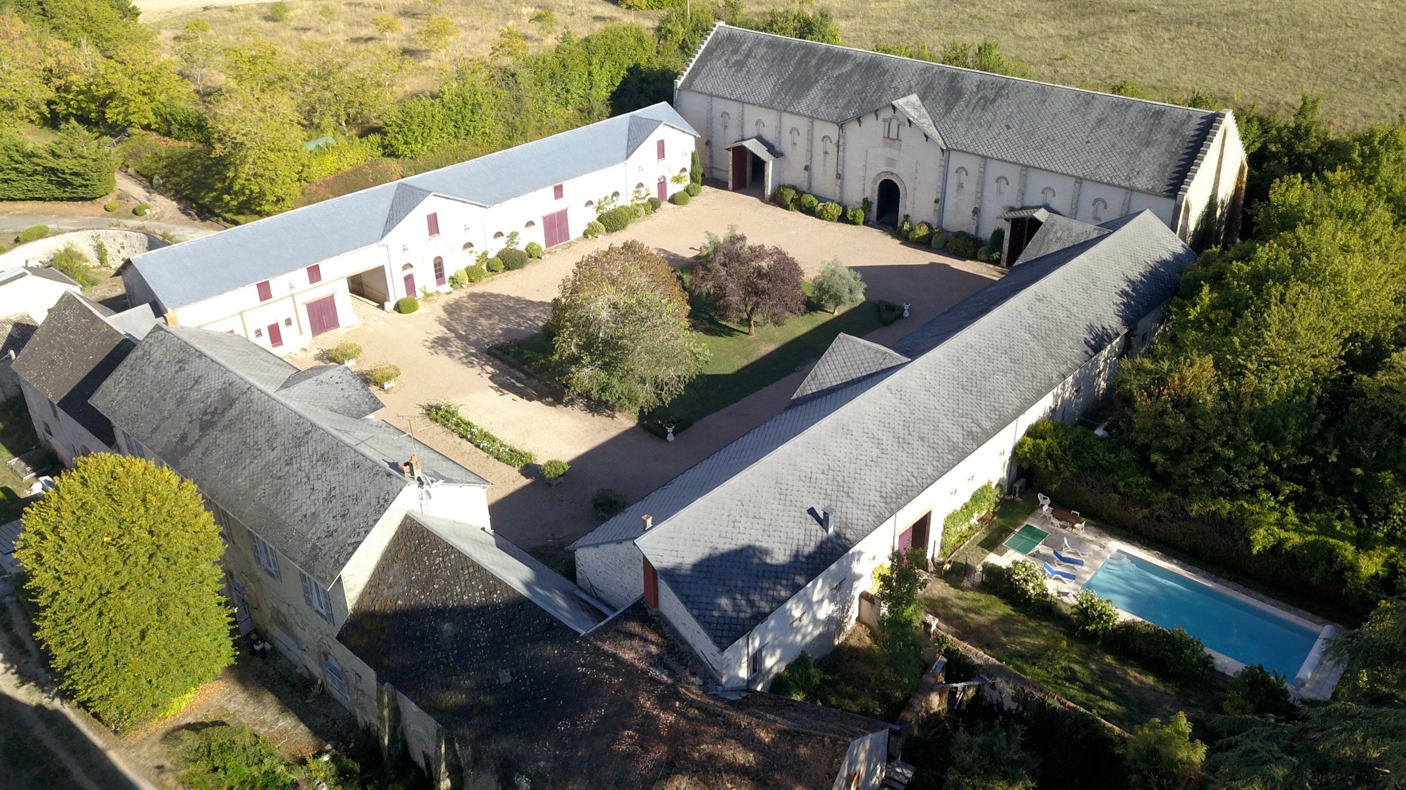 La cour du domaine vue depuis le porche de La Grange, portes bordeaux grandes ouvertes