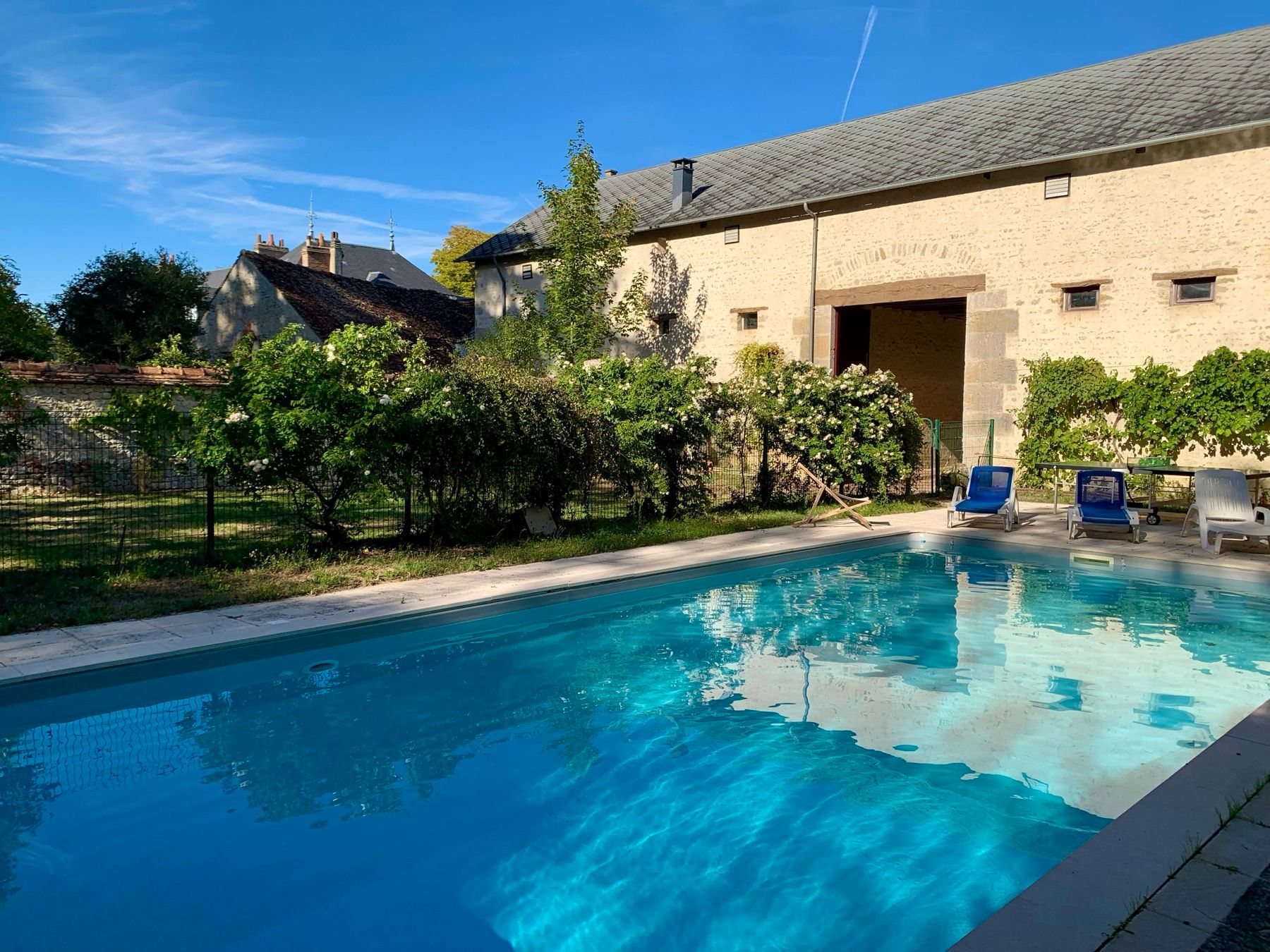 Le bassin chauffé du domaine, transats et façade en pierre en fond