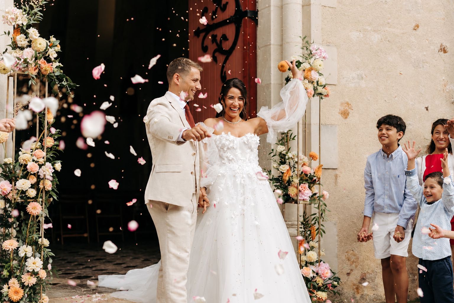 Les mariés sortent de l’église sous une pluie de confettis, entourés de leurs invités