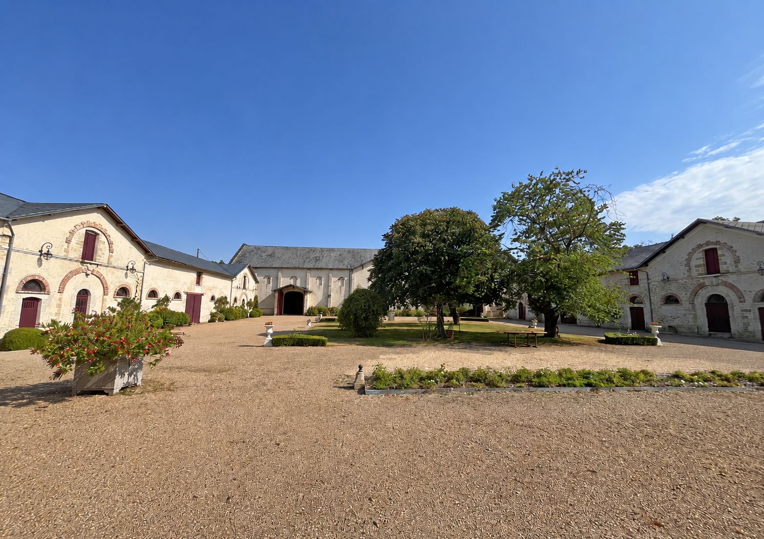 Vue de côté de la cour du domaine, les façades de La Plume, de La Grange et du gîte alignées